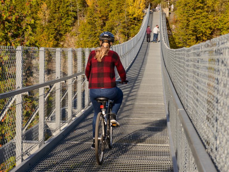 A person rides a bike across a suspension bridge