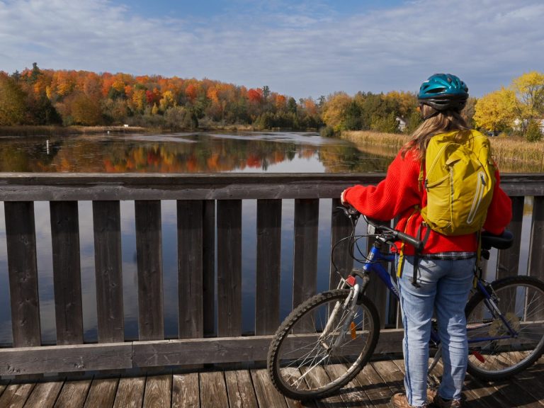 A woman stands with a bike and looks out across a body of water