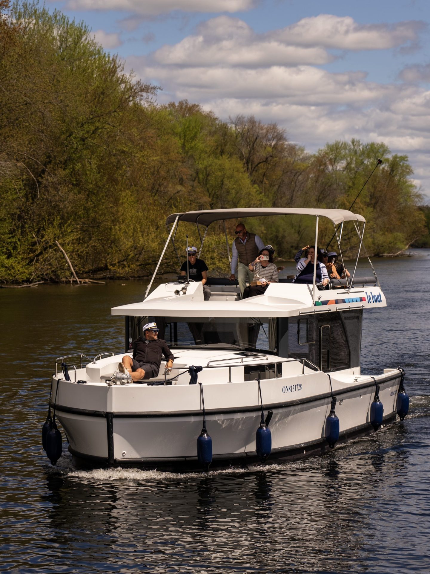 A house boat with several passengers navigates a channel