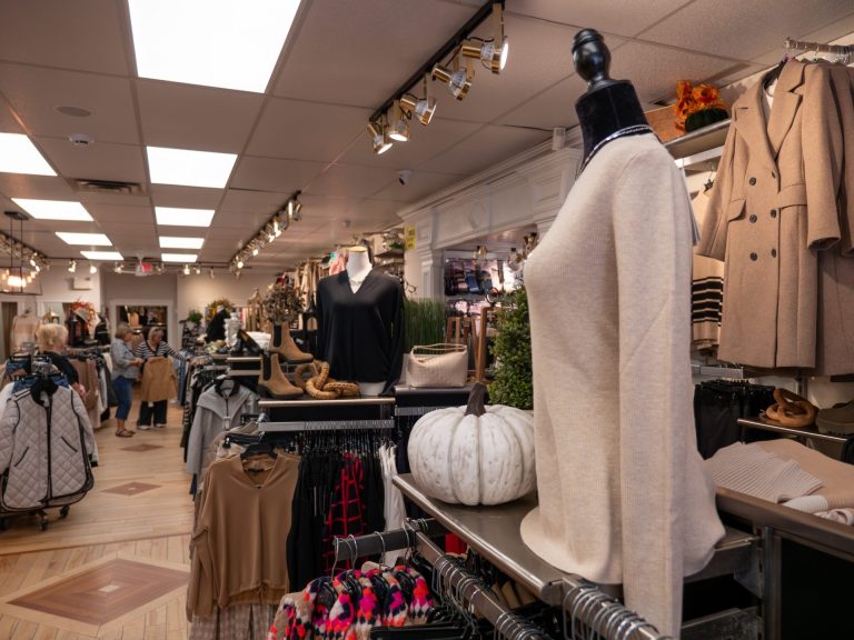 Interior of a clothing store, with a beige long-sleeved women's shirt in the foreground