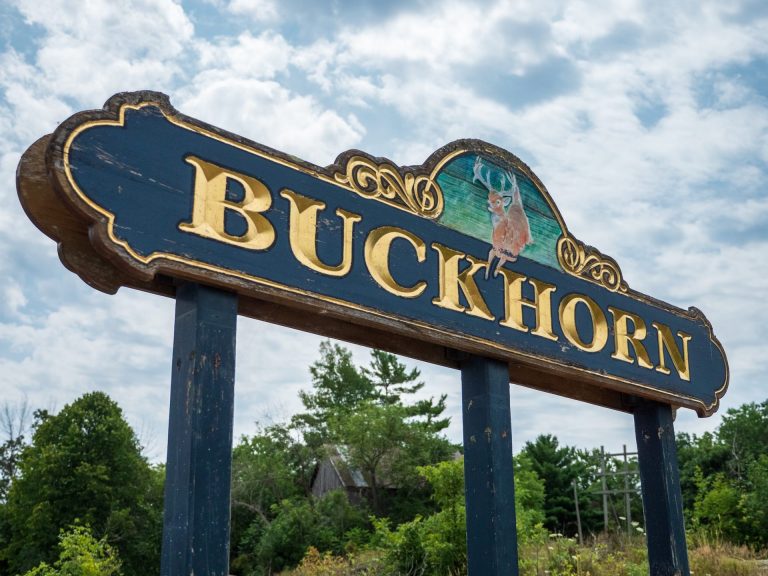 Wooden sign reading "Buckhorn," against a rocky landscape