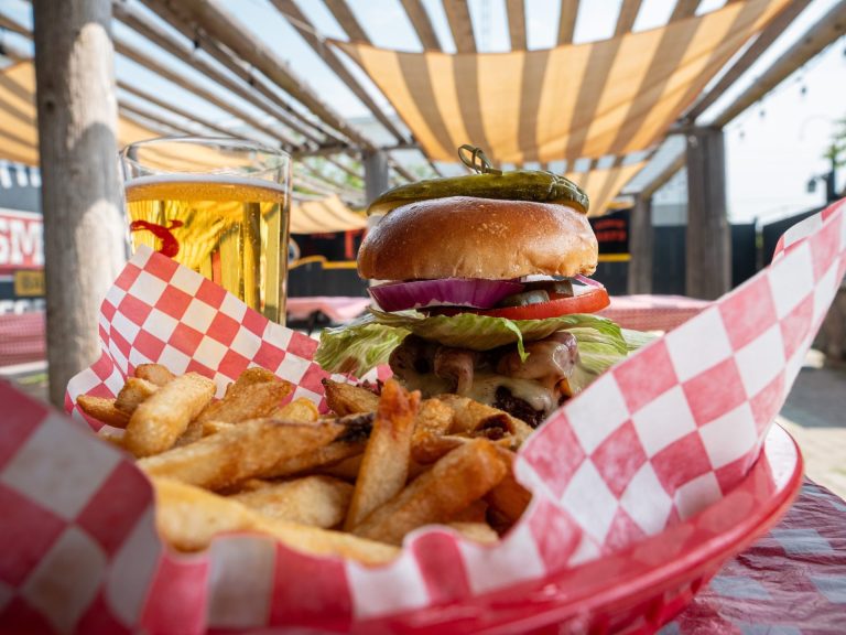 Burger, fries, and a pint of beer on a table on an outdoor patio