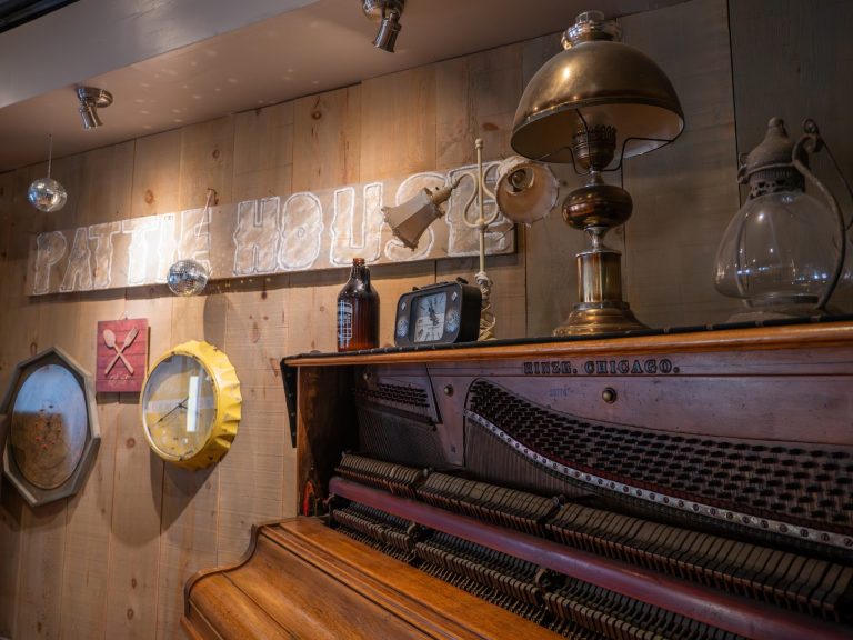 A lamp sits on top of an upright piano in the corner of a softly lit room