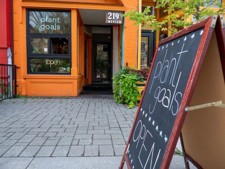 Sign reading Plant Goals - OPEN, with orange storefront in background