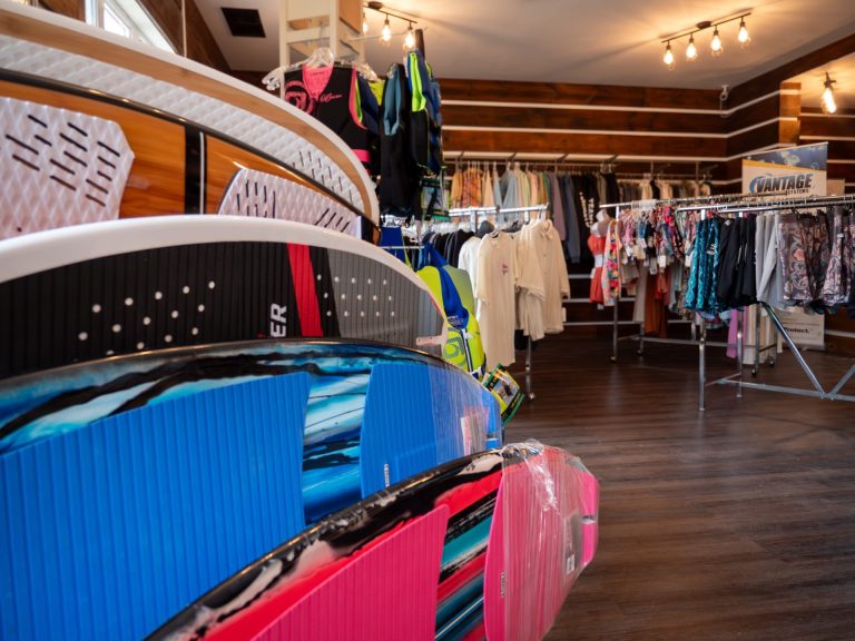 View of a display of paddle boards, with marine sports store in background