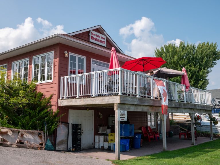 An elevated back patio on a red building with red umbrellas and Canada flags