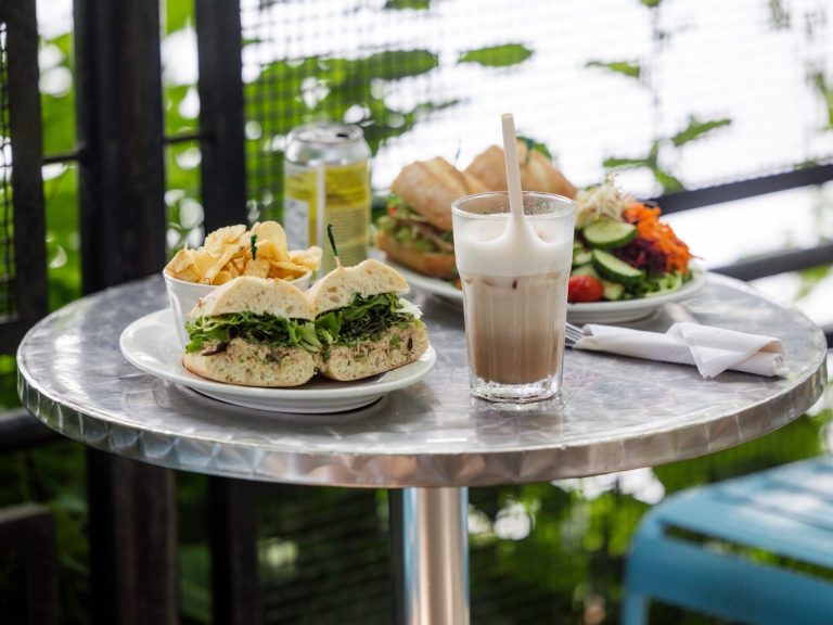 A sandwich and a cold coffee drink on a patio table