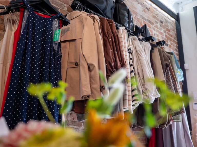 A rack of clothes in a retail shop, with flowers in the foreground