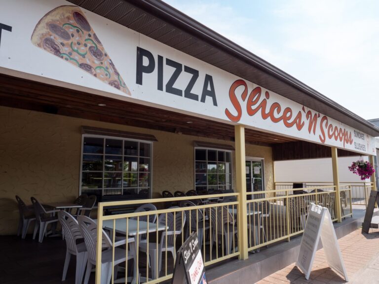 Exterior of Slices N' Scoops, with patio seating and image of slice of pizza