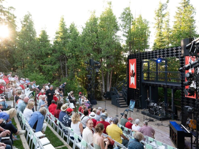 A crowd in an outdoor amphitheatre looks towards the open stage
